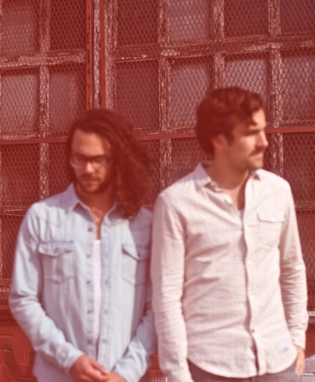 Tim Harrington and Paul Wright in front of a red wire-glass window, from the Neptune press shoot.